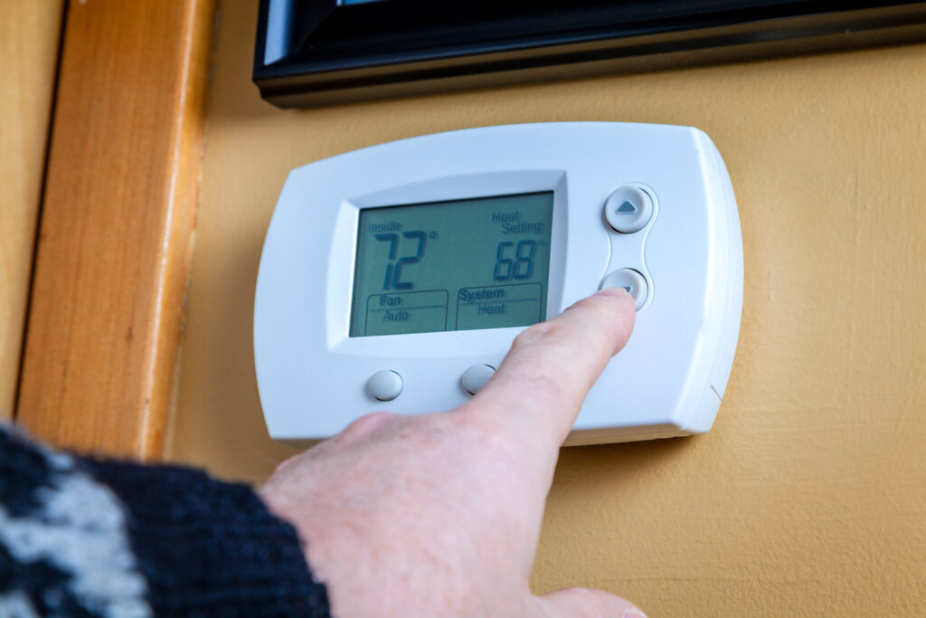 hand on thermostat adjusting it cooler