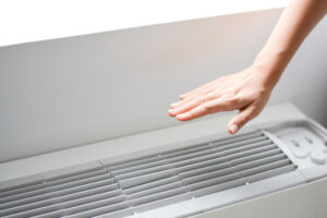%Imagetitle% | Grapids Home Services hand over HVAC heater and AC on wall to see if air is coming out