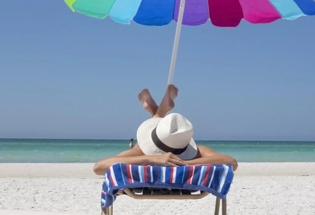 someone on vacation at beach laying in chair under umbrella