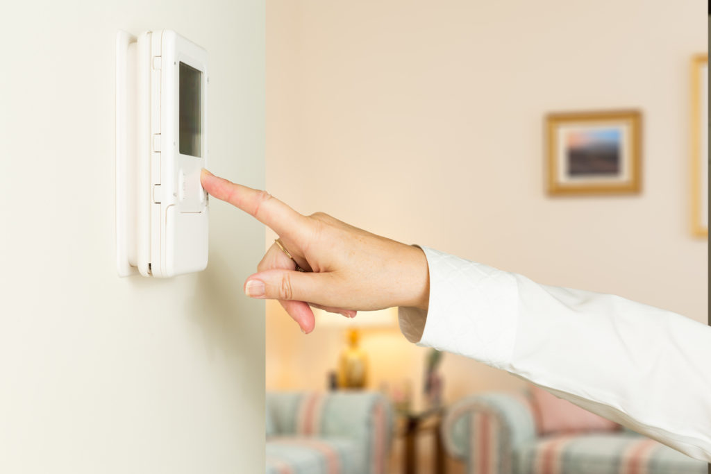 Woman adjusting wall thermostat