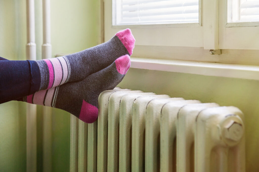 feet resting on the white, warm radiator