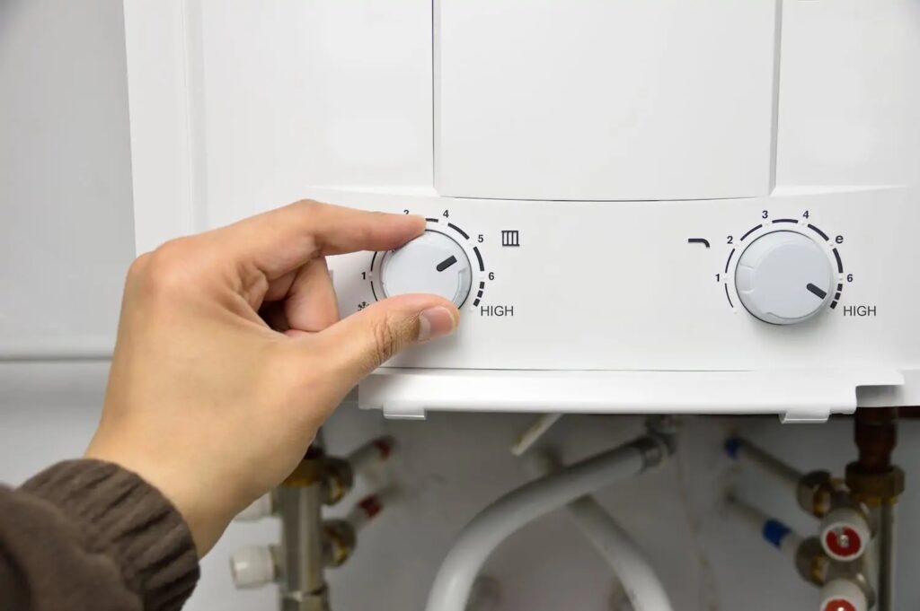 Hand adjusting the thermostat on a tankless water heater