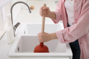 %Title% | Grapids Home Services person using plunger to unclog sink