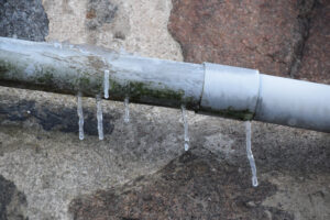 %Focuskw% | Grapids Home Services A frozen pipe with hanging icicles against a granite stone wall