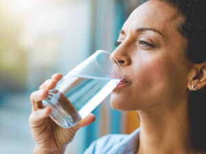 %Focuskw% | Grapids Home Services A person holding a clear glass of water, surrounded by soft natural light, with a serene indoor backdrop.
