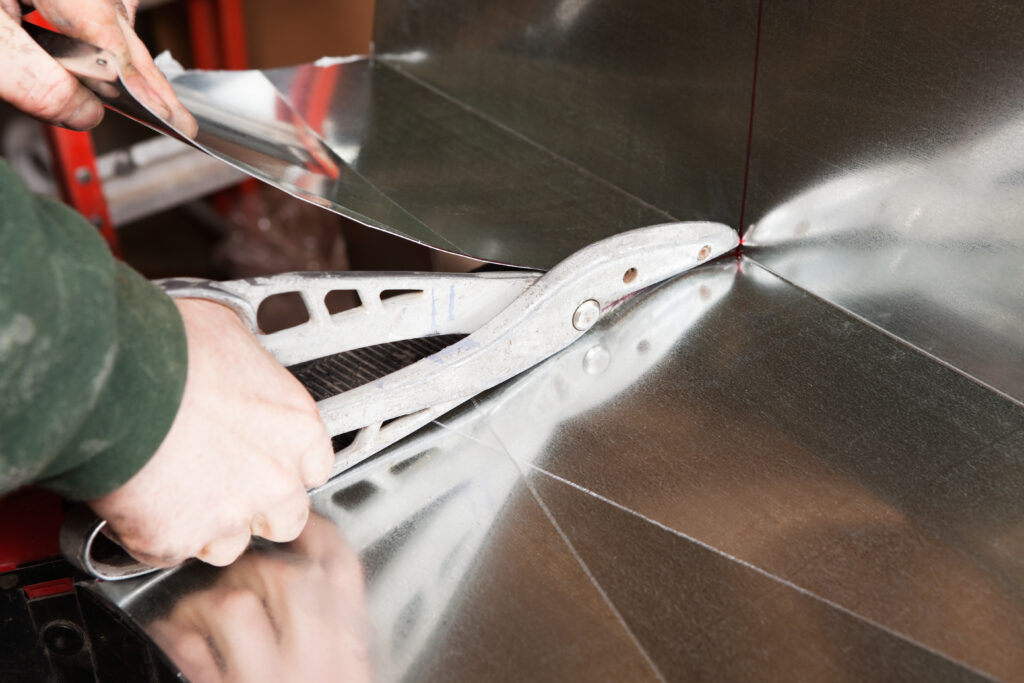 HVAC technician cutting sheet metal