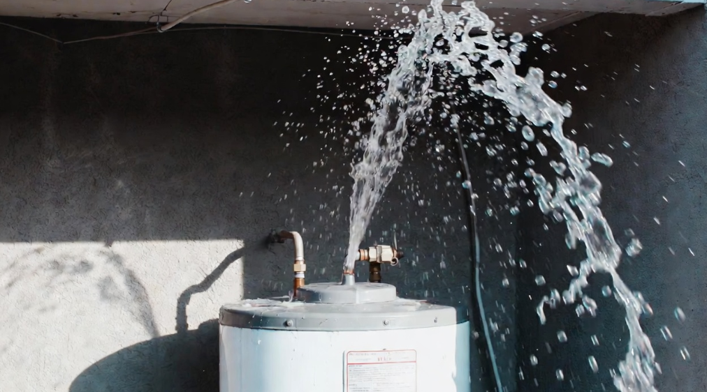 %Focuskw% | Grapids Home Services Water sprays forcefully from the top of a leaking water heater in a concrete-walled room, indicating a plumbing or equipment failure.