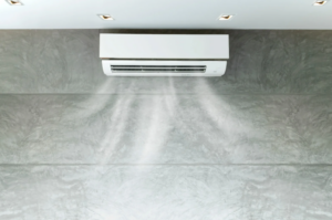 %Focuskw% | Grapids Home Services Wall-mounted air conditioner blowing cool air into a modern, grey-toned room with recessed ceiling lights.